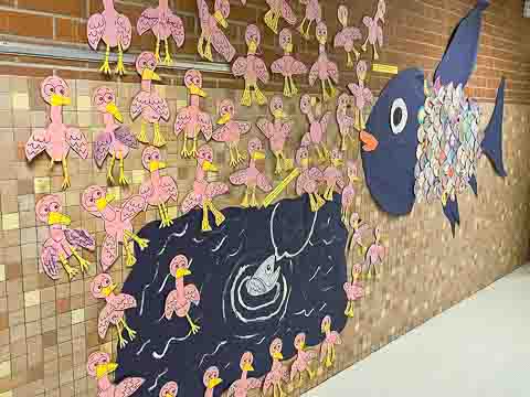 A fish pond surrounded by paper birds decorated by students covers a wall in our school.