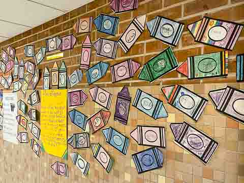 Paper crayons decorated by student fill a wall in our school.