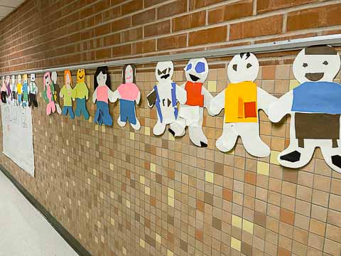 A row of paper people decorated by each student in front of Mr. Lopez' classroom.