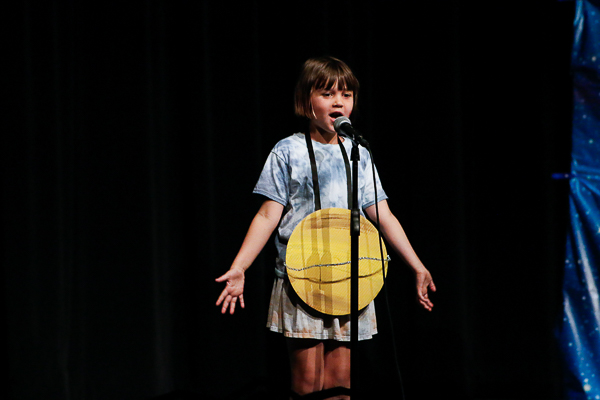 A performer dressed as a planet sings.